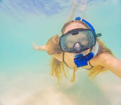 Woman with mask snorkeling in clear water.