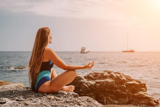 Woman sea yoga. Back view of free calm happy satisfied woman with long hair standing on top rock with yoga position against of sky by the sea. Healthy lifestyle outdoors in nature, fitness concept.