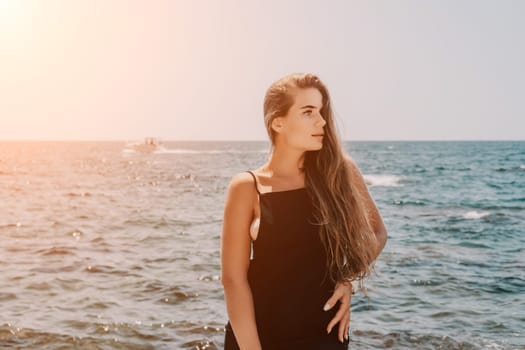 Woman travel sea. Young Happy woman in a long red dress posing on a beach near the sea on background of volcanic rocks, like in Iceland, sharing travel adventure journey