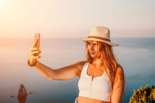 Woman travel sea. Happy tourist in hat enjoy taking picture outdoors for memories. Woman traveler posing on the beach at sea surrounded by volcanic mountains, sharing travel adventure journey