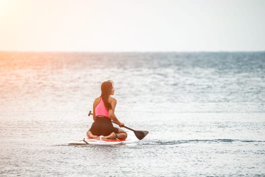 Sea woman and man on sup. Silhouette of happy young woman and man, surfing on SUP board, confident paddling through water surface. Idyllic sunset. Active lifestyle at sea or river