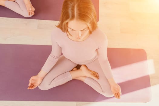 Young woman with long hair in white swimsuit and boho style braclets practicing outdoors on yoga mat by the sea on a sunset. Women's yoga fitness routine. Healthy lifestyle, harmony and meditation