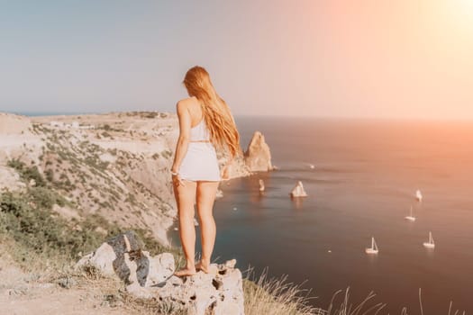 Woman travel sea. Young Happy woman in a long red dress posing on a beach near the sea on background of volcanic rocks, like in Iceland, sharing travel adventure journey