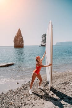 Close up shot of beautiful young caucasian woman with black hair and freckles looking at camera and smiling. Cute woman portrait in a pink bikini posing on a volcanic rock high above the sea