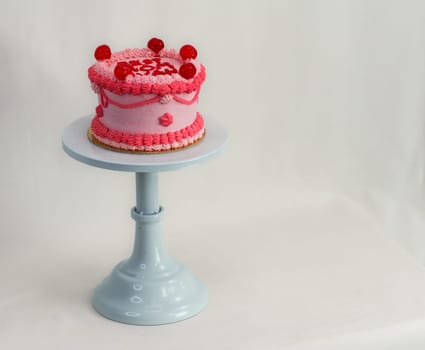 frosted pink red cake for mothers day celebration with funny text topping best mom evah on white studio background