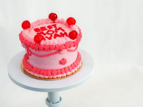 frosted pink red cake for mothers day celebration with funny text topping best mom evah on white studio background