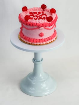 frosted pink red cake for mothers day celebration with funny text topping best mom evah on white studio background