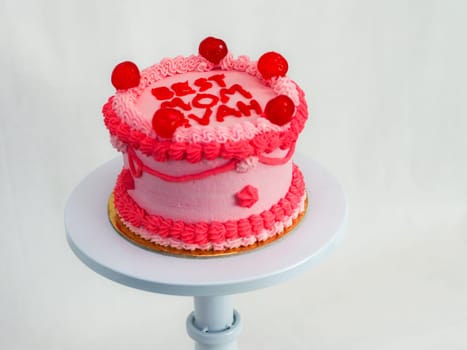 frosted pink red cake for mothers day celebration with funny text topping best mom evah on white studio background
