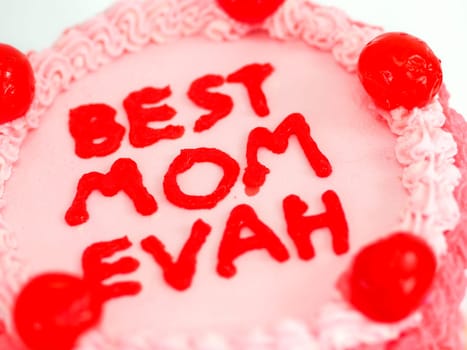 frosted pink red cake for mothers day celebration with funny text topping best mom evah on white studio background