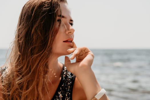 Woman travel sea. Young Happy woman in a long red dress posing on a beach near the sea on background of volcanic rocks, like in Iceland, sharing travel adventure journey