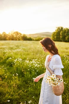 vertical portrait of a beautiful woman in a light dress with a basket full of daisies in nature. High quality photo