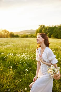 vertical portrait of a beautiful woman in a light dress with a basket full of daisies in nature. High quality photo