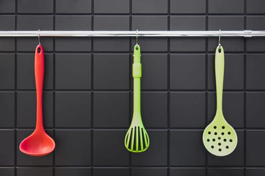Silicone cooking utensils hanging in the kitchen on the backsplash.