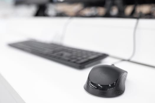 Minimalistic computer workplace with computer mouse in focus and keyboard out of focus.