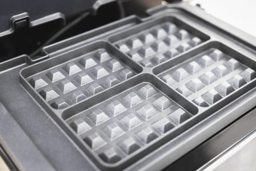Close-up of a new 4-section electric waffle maker for home cooking.