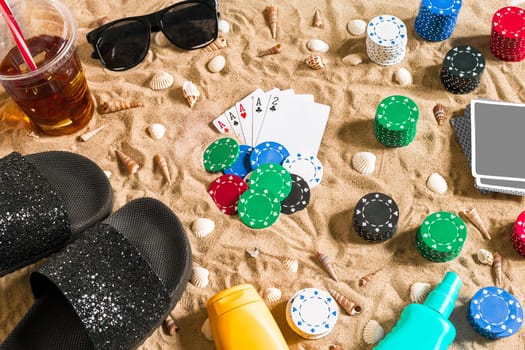 Gambling on vacation concept - white sand with seashells , colored poker chips and cards. Top view. Copy space. Summer