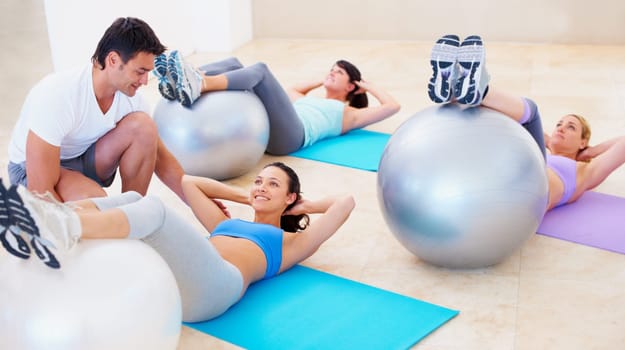Personal trainer, pilates and ball for helping women with balance, posture and happy for training, fitness and gym. Man, exercise and help woman in class with stretching, wellness or workout on floor.