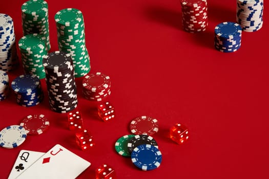 Two cards and chips on a red background. Big bet of game money. Cards - the queen and the jack. Your distribution at the table. Casino background. Copy space. Still life.