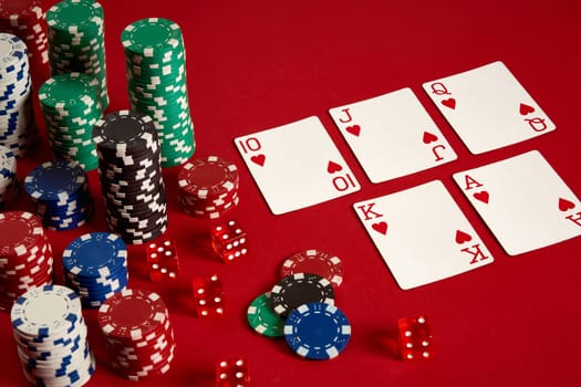 Casino gambling poker equipment and entertainment concept - close up of playing cards and chips at red background. Royal flush heart. Casino background. Copy space. Still life