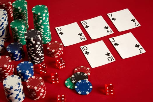 Casino gambling poker equipment and entertainment concept - close up of playing cards and chips at red background. Straight Flush. Casino background. Copy space. Still life