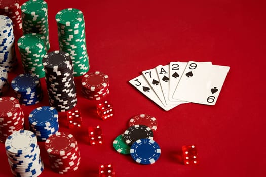 Casino gambling poker equipment and entertainment concept - close up of playing cards and chips at red background. Flush. Casino background. Copy space. Still life