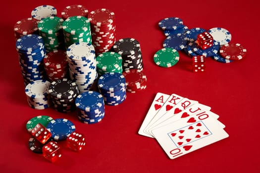 Casino gambling poker equipment and entertainment concept - close up of playing cards and chips at red background. Royal flush heart. Casino background. Copy space. Still life