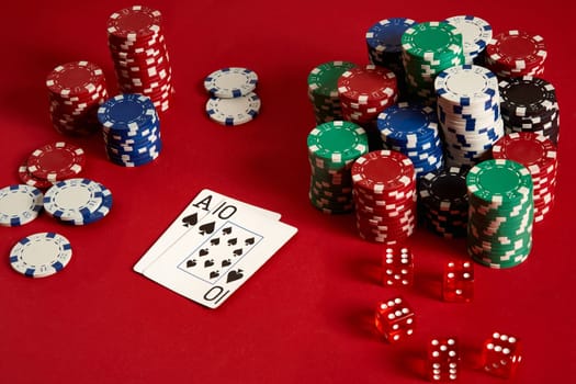 Two cards and chips on a red background. Big bet of game money. Cards - Ace and Ten. Your distribution at the table. Casino background. Copy space. Still life.