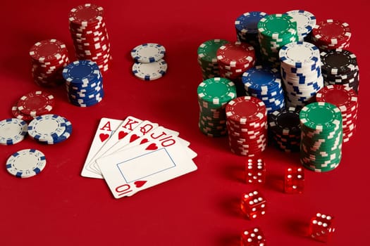 Casino gambling poker equipment and entertainment concept - close up of playing cards and chips at red background. Royal flush heart. Casino background. Copy space. Still life