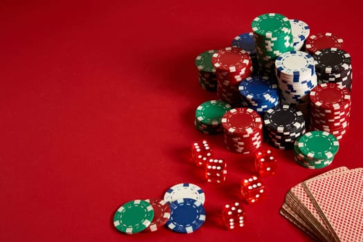 Poker chips and Card deck on red background. Group of different poker chips. Casino background. Copy space. Still life