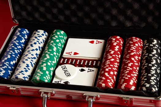 Poker set in metal suitcase. Risky entertainment of gambling. Top view on red background. Casino background. Copy space. Still life.