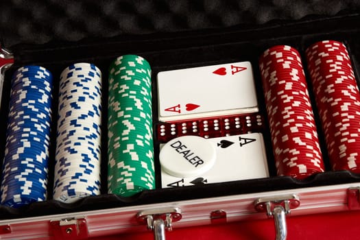 Poker set in metal suitcase. Risky entertainment of gambling. Top view on red background. Casino background. Copy space. Still life.