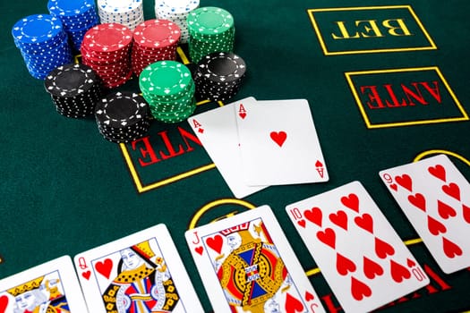 Poker play. Chips and cards on the green table