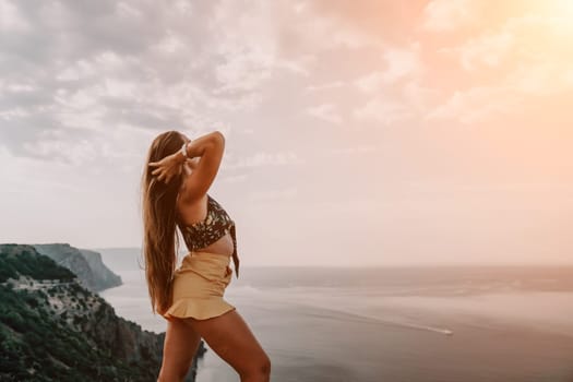 Woman travel sea. Happy tourist taking picture outdoors for memories. Woman traveler looks at the edge of the cliff on the sea bay of mountains, sharing travel adventure journey.