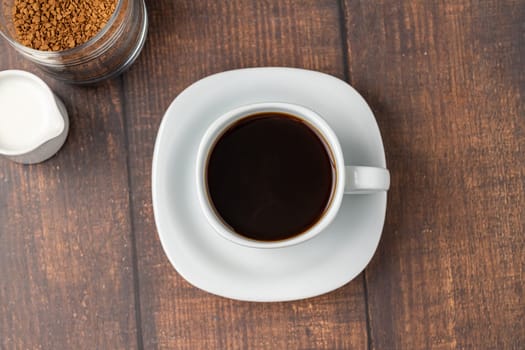 Instant or granulated coffee in white cup on wooden table