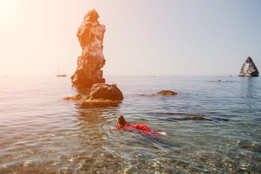 Woman travel sea. Happy tourist taking picture outdoors for memories. Woman traveler looks at the edge of the cliff on the sea bay of mountains, sharing travel adventure journey.