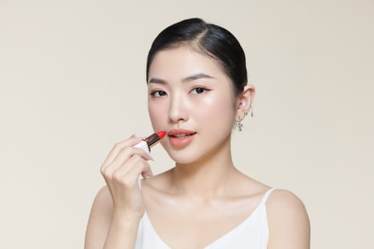 Portrait of gorgeous smiling woman holding red lipstick in hand
