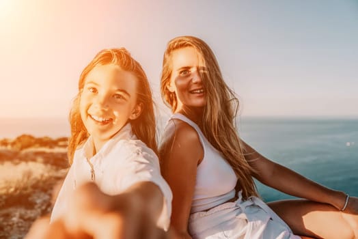 Close up portrait of mom and her teenage daughter hugging and smiling together over sunset sea view. Beautiful woman relaxing with her child.