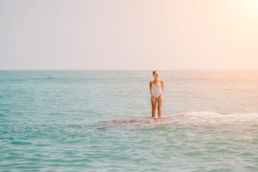 Woman sea yoga. Back view of free calm happy satisfied woman with long hair standing on top rock with yoga position against of sky by the sea. Healthy lifestyle outdoors in nature, fitness concept.