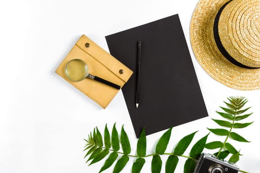 Straw hat with green leaves and old camera on white background, Summer background. Top view. Copy space. Still life. Flat lay