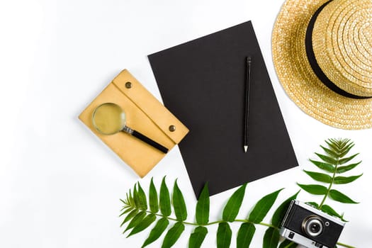 Straw hat with green leaves and old camera on white background, Summer background. Top view. Copy space. Still life. Flat lay