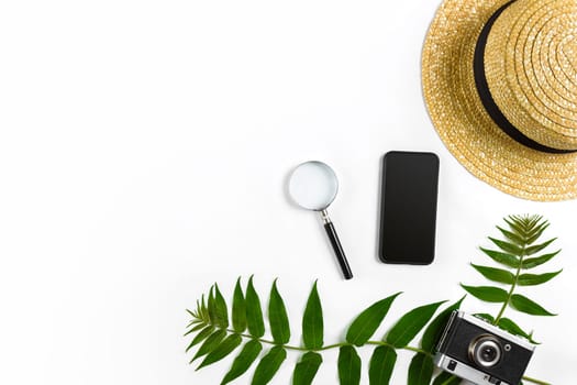 Straw hat with green leaves and old camera on white background, Summer background. Top view. Copy space. Still life. Flat lay