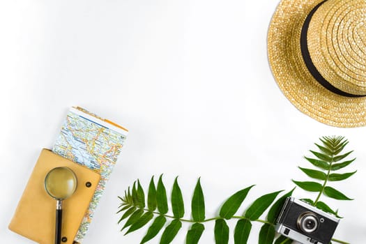 Straw hat with green leaves and old camera on white background, Summer background. Top view. Copy space. Still life. Flat lay