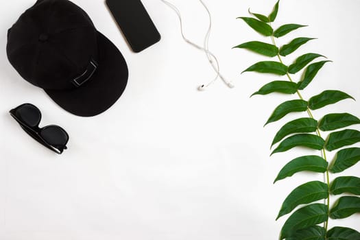 Travel accessories set on white background: smart, headphones, cap and sunglasses. Top view point. Flat lay. Still life. Copy space