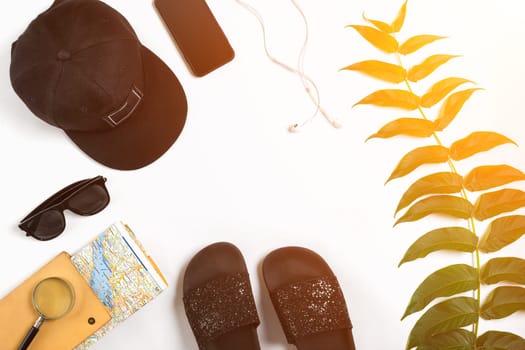 Travel accessories set on white background: smart, headphones, cap, map and sunglasses. Top view point. Flat lay. Still life. Copy space. Sun flare