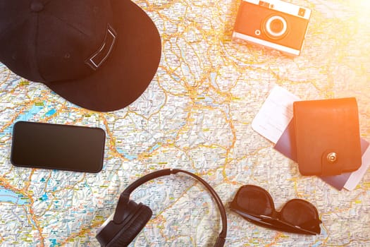 Accessories for travel. Passport, photo camera, smart phone and travel map. Top view. Holidays and tourism concept. Copy space. Still life. Flat lay. Sun flare