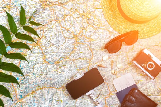 Accessories for travel. Passport, photo camera, smart phone and travel map. Top view. Holidays and tourism concept. Copy space. Still life. Flat lay. Sun flare