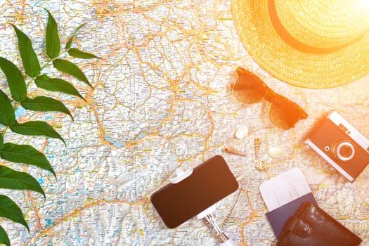 Accessories for travel. Passport, photo camera, smart phone and travel map. Top view. Holidays and tourism concept. Copy space. Still life. Flat lay. Sun flare