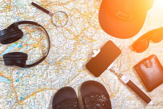 Accessories for travel. Passport, cap, smart phone and travel map. Top view. Holidays and tourism concept. Copy space. Still life. Flat lay. Sun flare