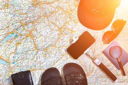 Accessories for travel. Passport, cap, smart phone and travel map. Top view. Holidays and tourism concept. Copy space. Still life. Flat lay. Sun flare