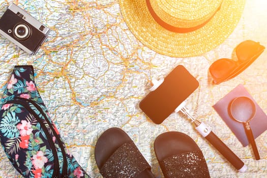 Accessories for travel. Passport, hat, smart phone and travel map. Top view. Holidays and tourism concept. Copy space. Still life. Flat lay. Sun flare